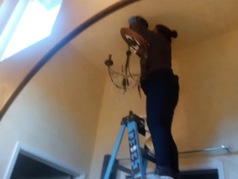 Electrician installing a chandelier in a Bloomington residence